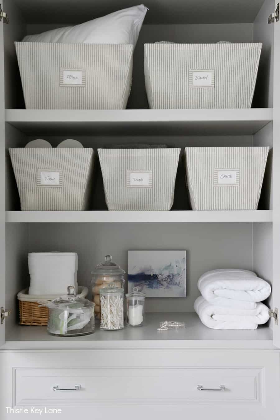 Shelves with bins and folded towels. Organizing A Master Bathroom Linen Closet.