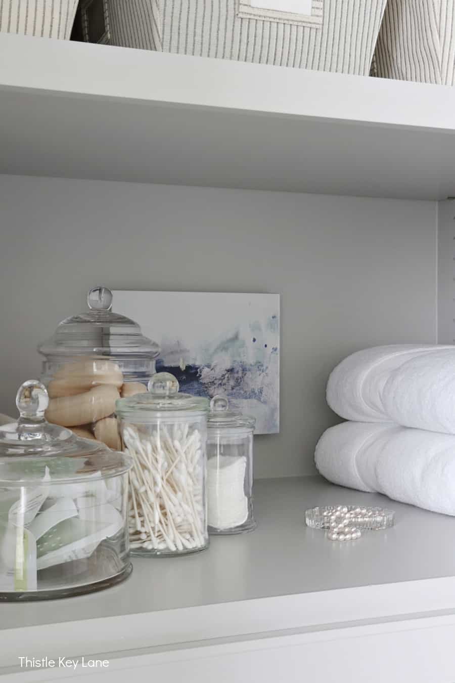 Glass storage jars and abstract artwork. Organizing A Master Bathroom Linen Closet.