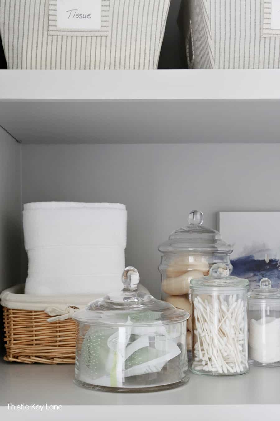 Glass storage jars on linen closet shelf. 