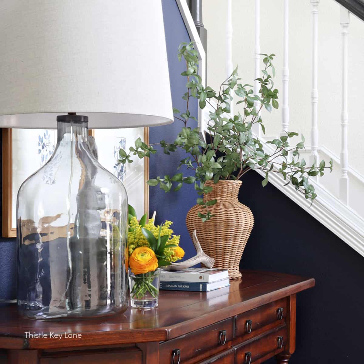 Yellow flowers, glass lamp and wicker vase with stems.