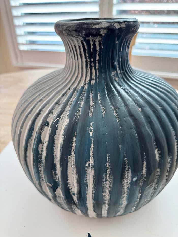 Applying paint to vase.