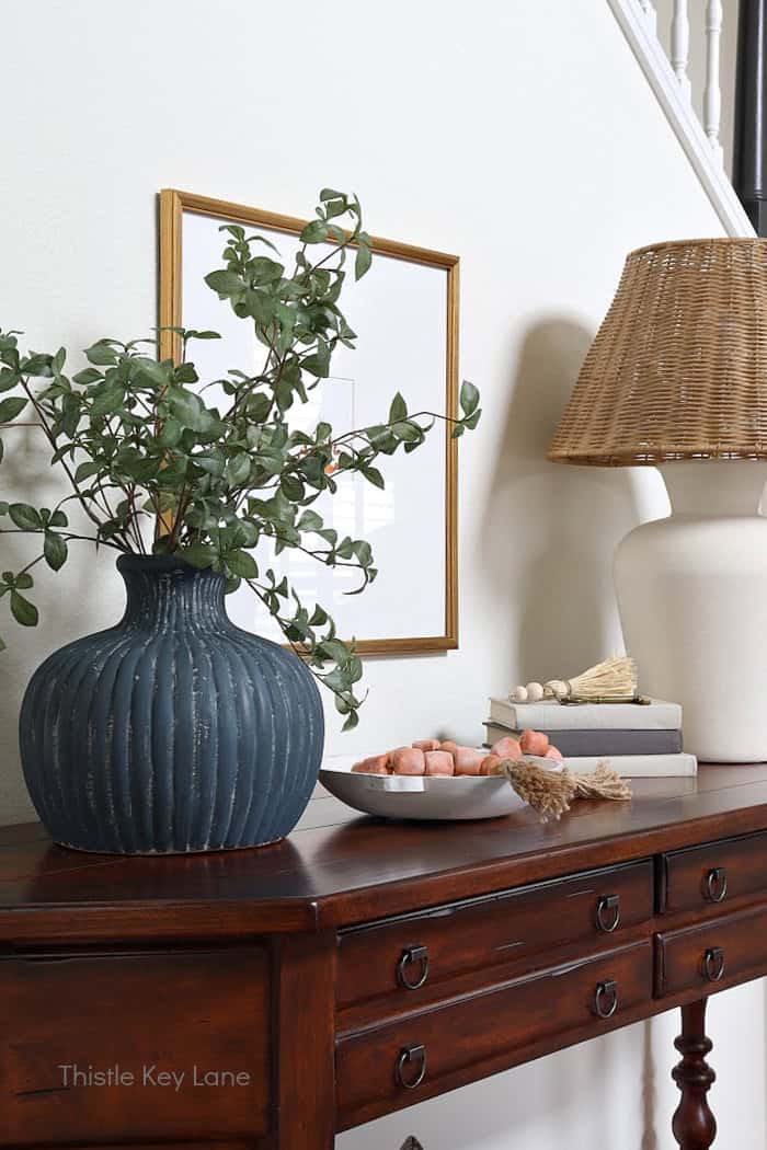 Blue vase, white bowl, stack of books, lamp. Entry Table Update With A Vase Makeover