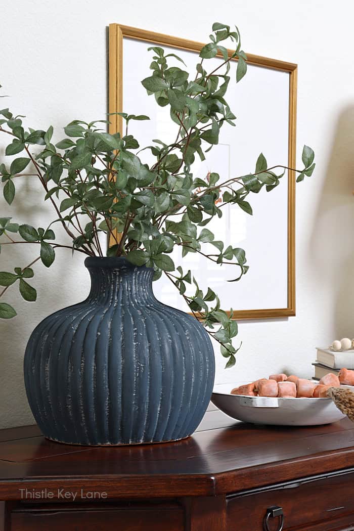 Green stems in a large blue vase on a table. Entry Table Update With A Vase Makeover.