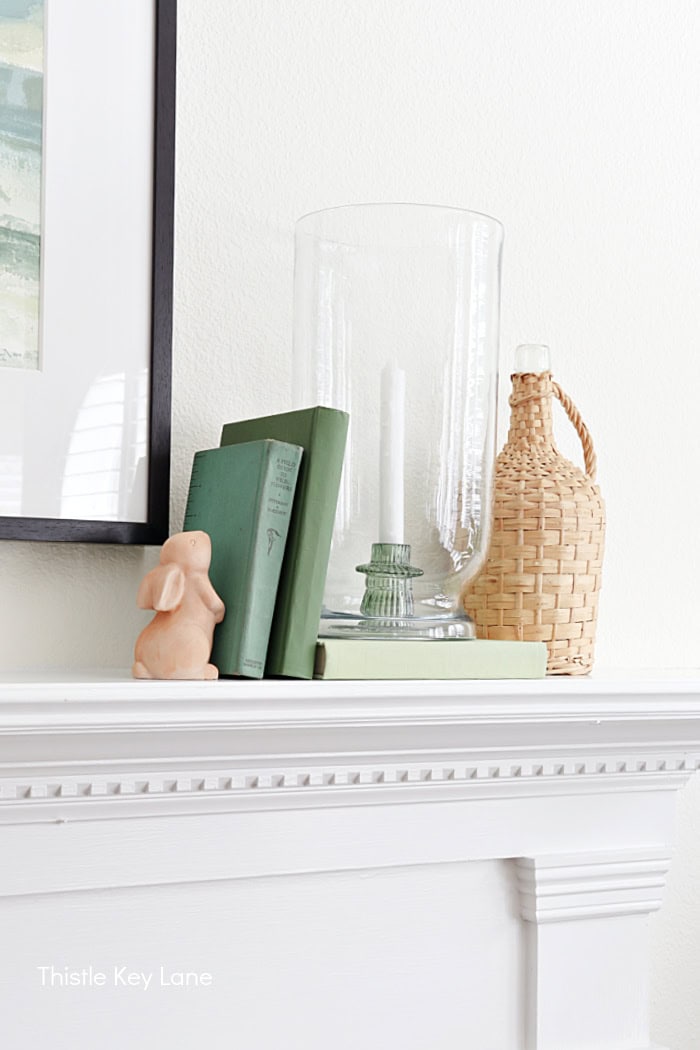 Ribbit figure, green books, hurricane candle holder, vintage wine bottle.