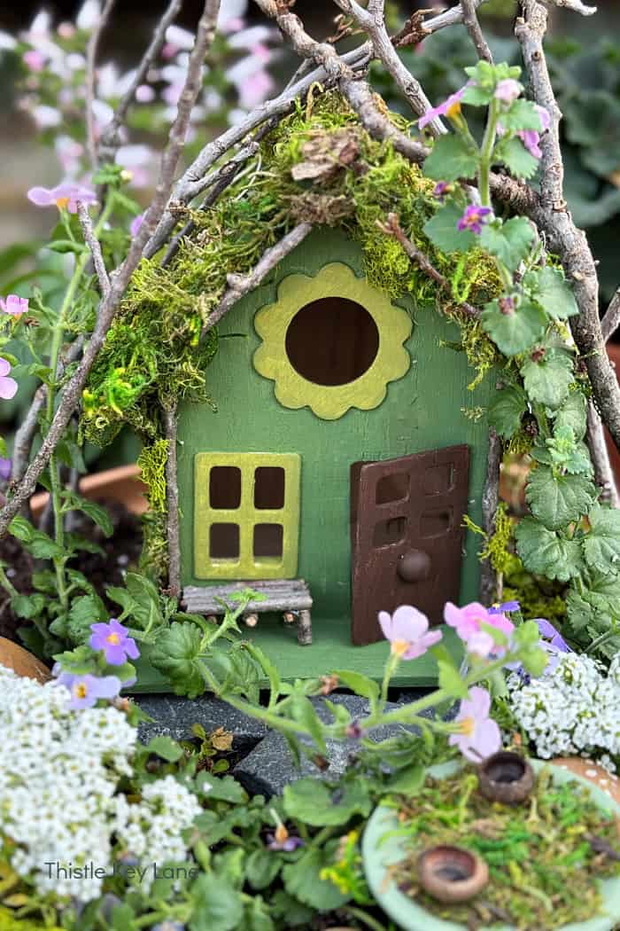 Front view of bird house painted green. How To Make A Flower Pot Fairy Garden.