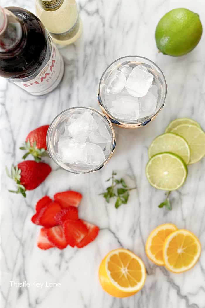 Sliced fruit, glasses of ice and bottles.
