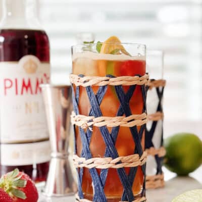 Tall drink in wicker wrapped glass. Pimm's Cup Cocktail Recipe.