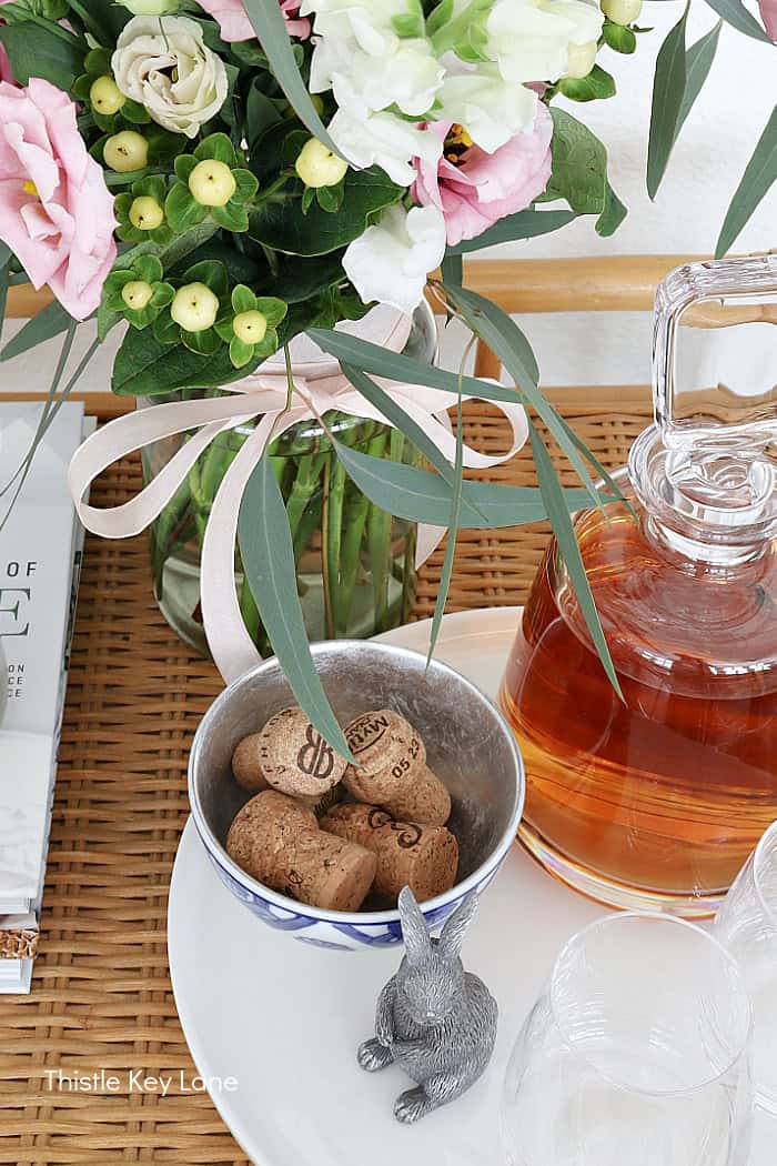 Bar cart decanter, flowers, corks and bunny figurine.