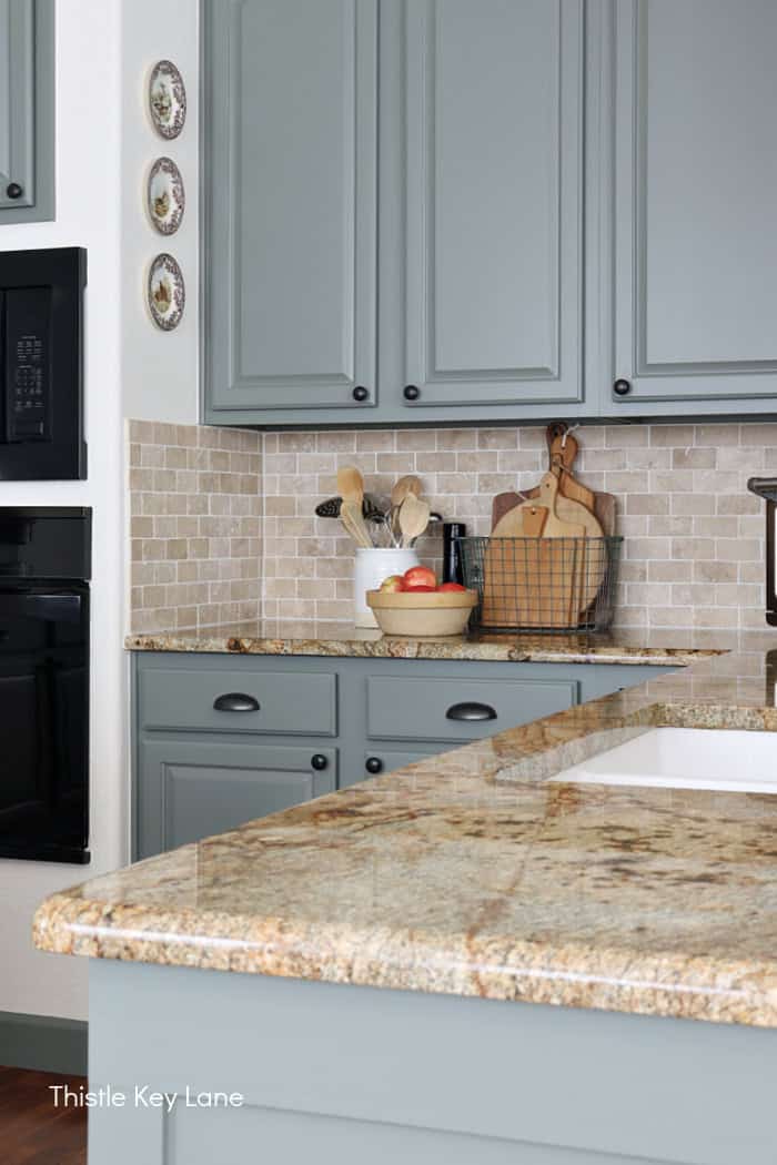View of green kitchen cabinets and granite counters. Soft Neutrals Spring Home Tour.