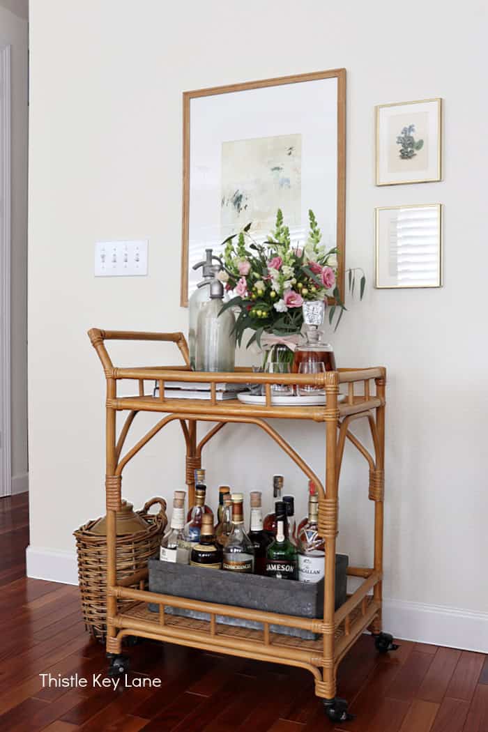 Wicker bar cart with bottles and flowers. Soft Neutrals Spring Home Tour.