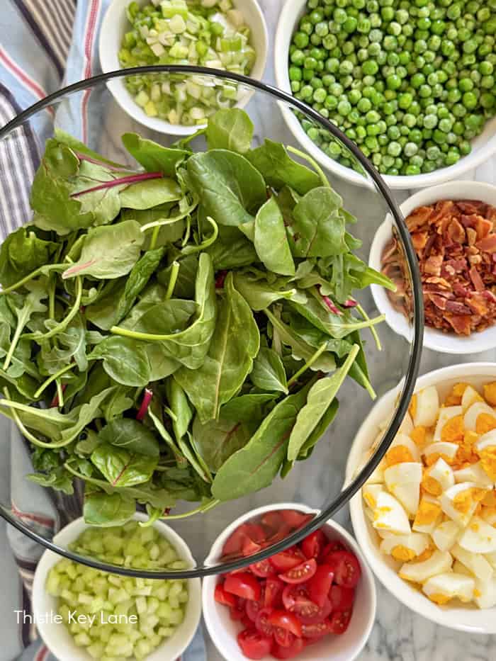 Lettuce, green peas, green onions, bacon, hard boiled eggs, celery and tomatoes.