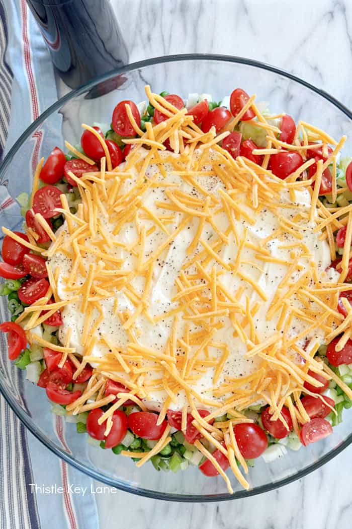 Mayo dressing and cheese on top of salad. Green Pea Layered Salad Recipe.