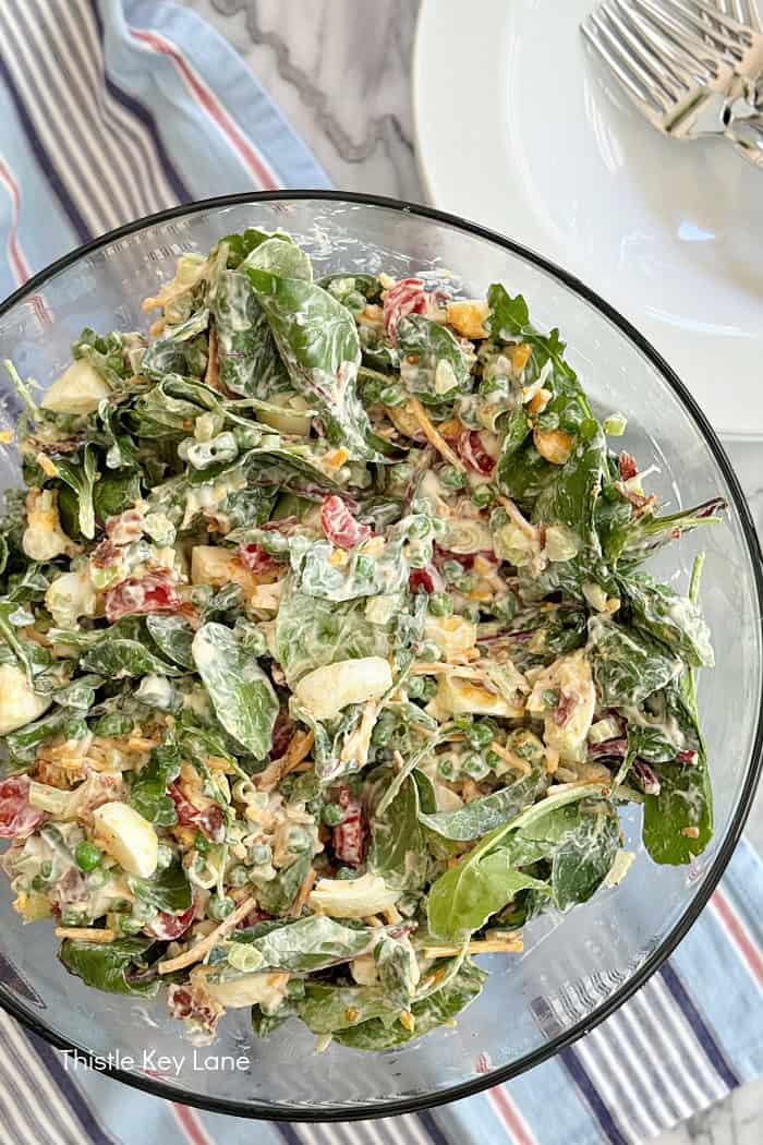 Tossed salad with lettuce, peas, bacon and eggs.
