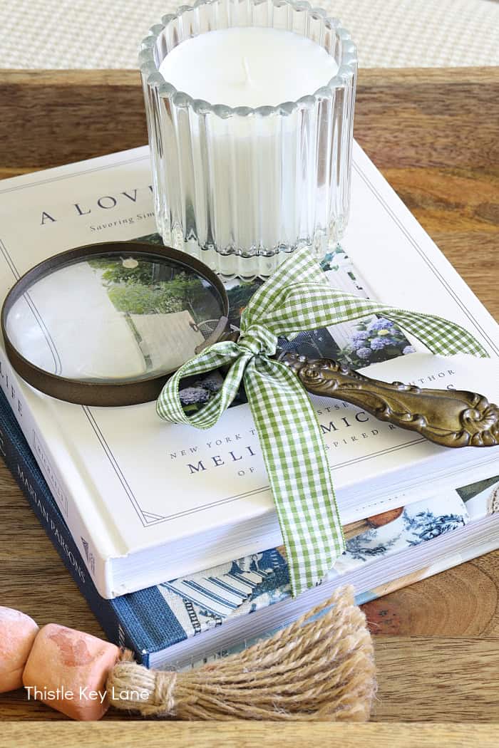 Magnifying glass with ribbon on books. Summer Fresh Ottoman Styling.