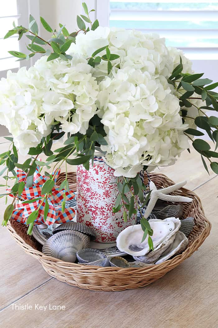 A basket with white flowers and shells on a table. Summer Red White And Blue Centerpiece 