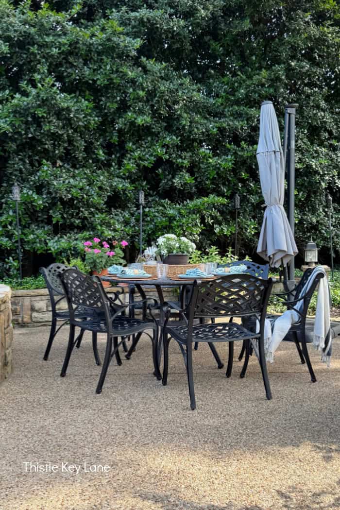 A patio table and chairs in a garden. Breezy Summer Patio Tour.