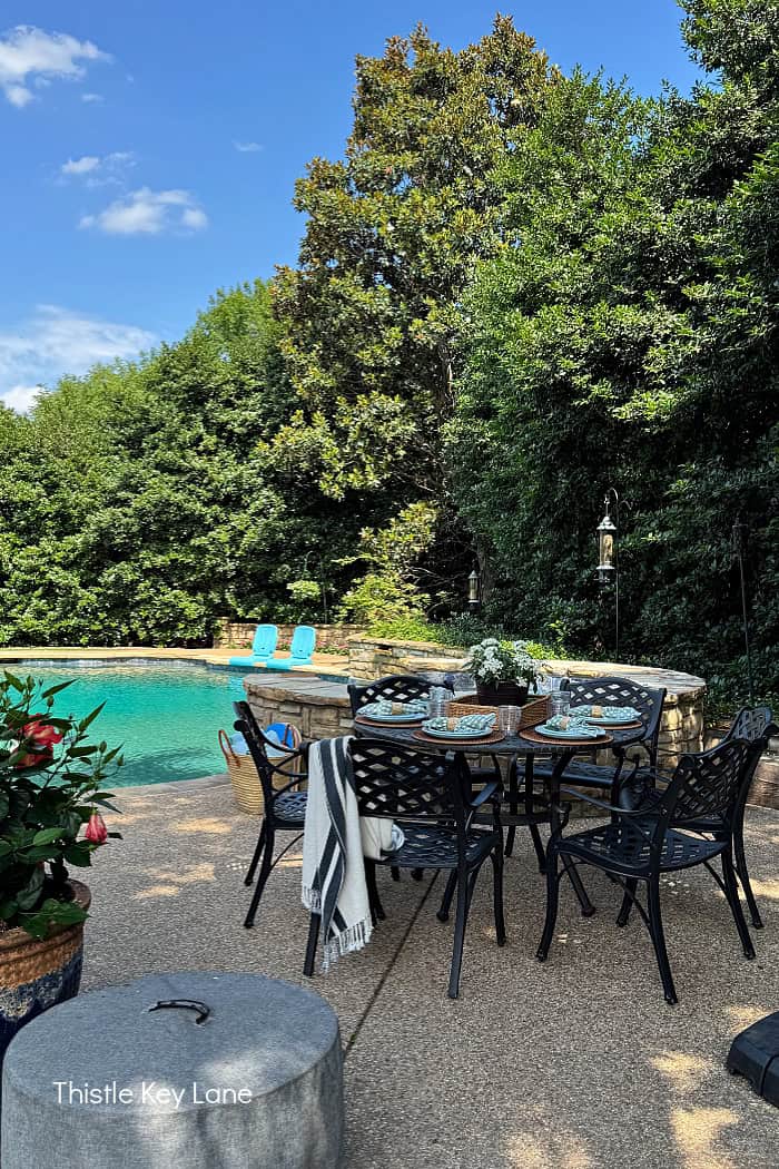 A table and chairs with a pool in the background. Breezy Summer Patio Tour.