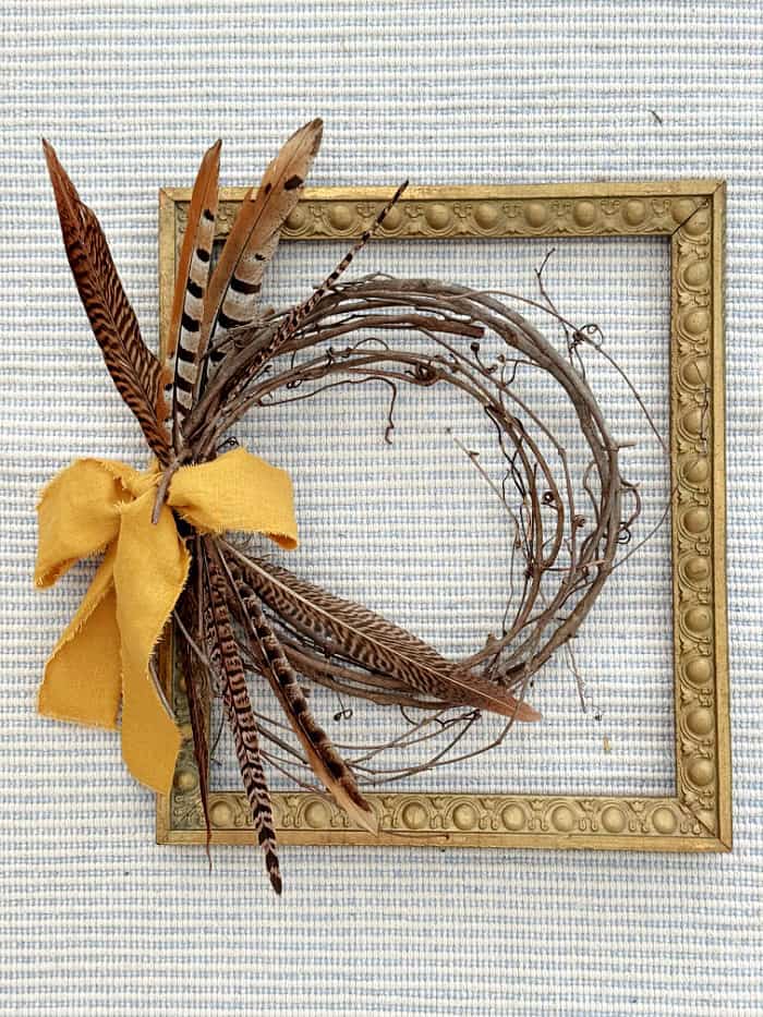 Adding a ribbon to the wreath and frame. DIY Vintage Frame Wreath With Feathers.