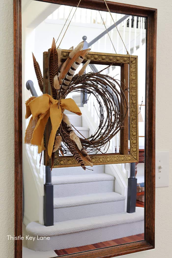 Displaying a wreath on top of a frame. DIY Vintage Frame Wreath With Feathers.