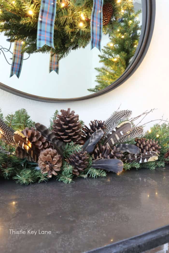 Greenery with pinecones and feathers.