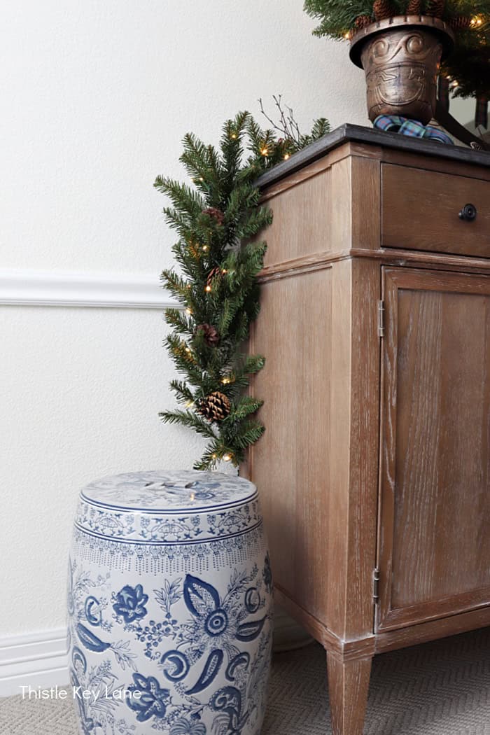 Side of a table with ceramic stool and greenery. Christmas Decorating.
