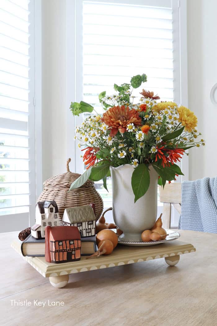 Orange and gold flowers, vase, wooden platform, fall accents. Autumn Vintage Cottage Vignette.