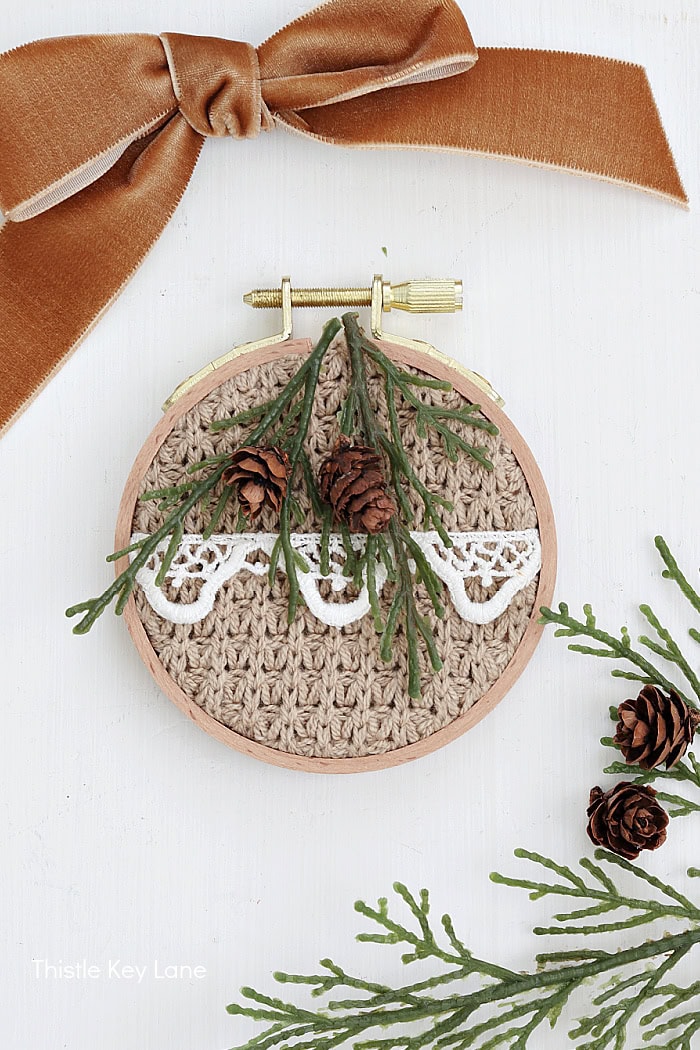 Adding greenery and pinecones to sweater ornament. Embroidery Hoop Ornaments From Sweaters.