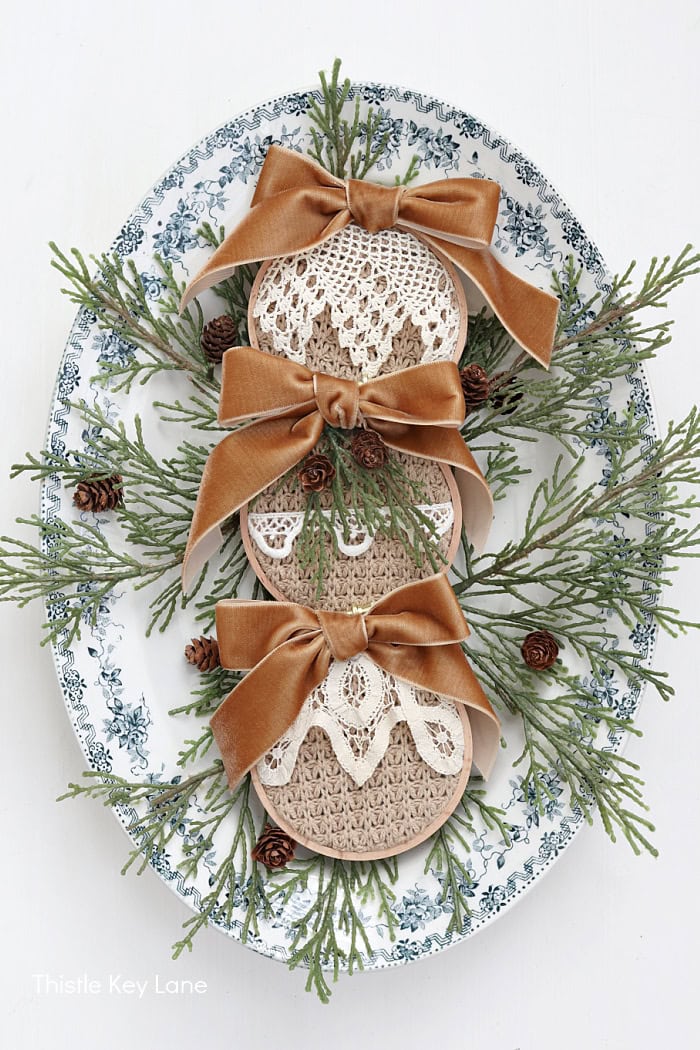 Ornaments on a platter with greenery. Embroidery Hoop Ornaments From Sweaters.