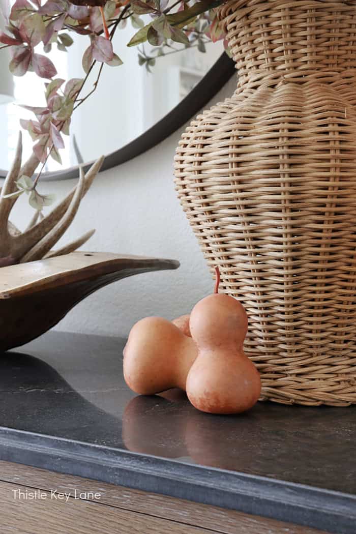 Bottle neck gourds next to a wicker vase. 