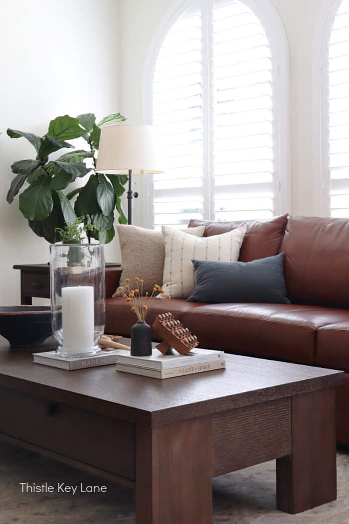 Cozy living room with leather sofa, large window shutters, and stylish decor. Cozy Autumn Family Room Decor.