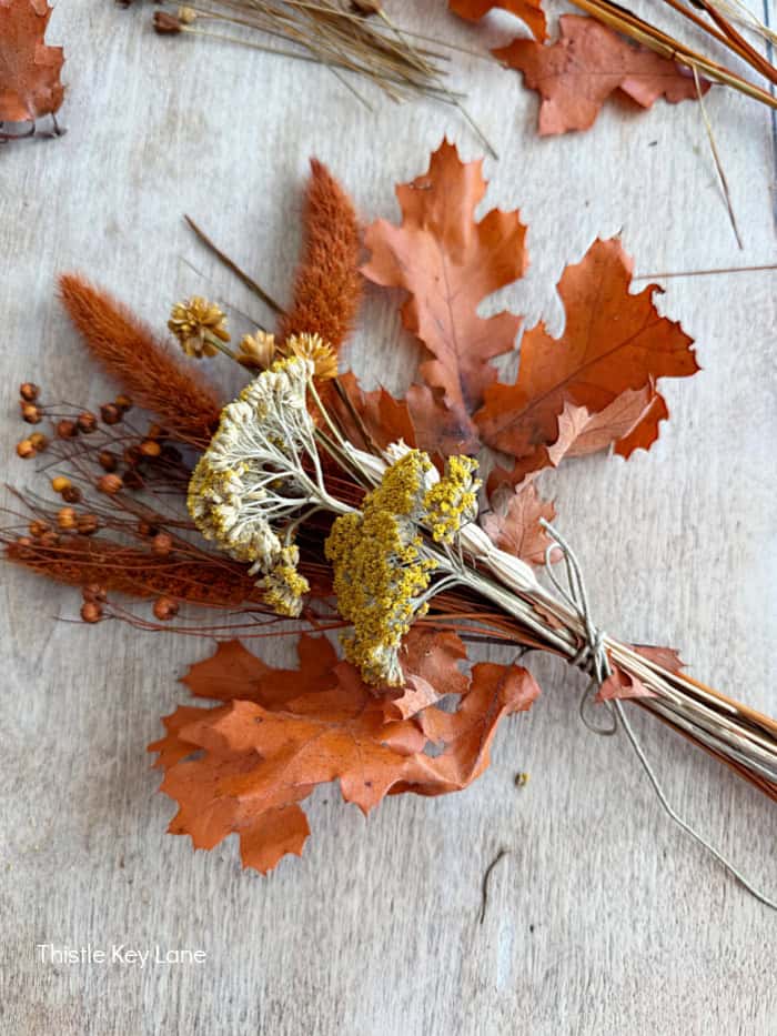 Orange leaves, grasses and dried flowers. Fall Dried Florals Book Vignette.