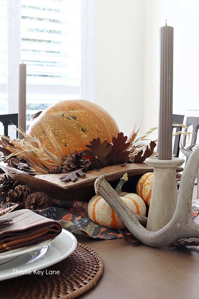 Orange pumpkin, brown leaves, candle holders. Rustic Thanksgiving Pumpkin Centerpiece And Tablescape.