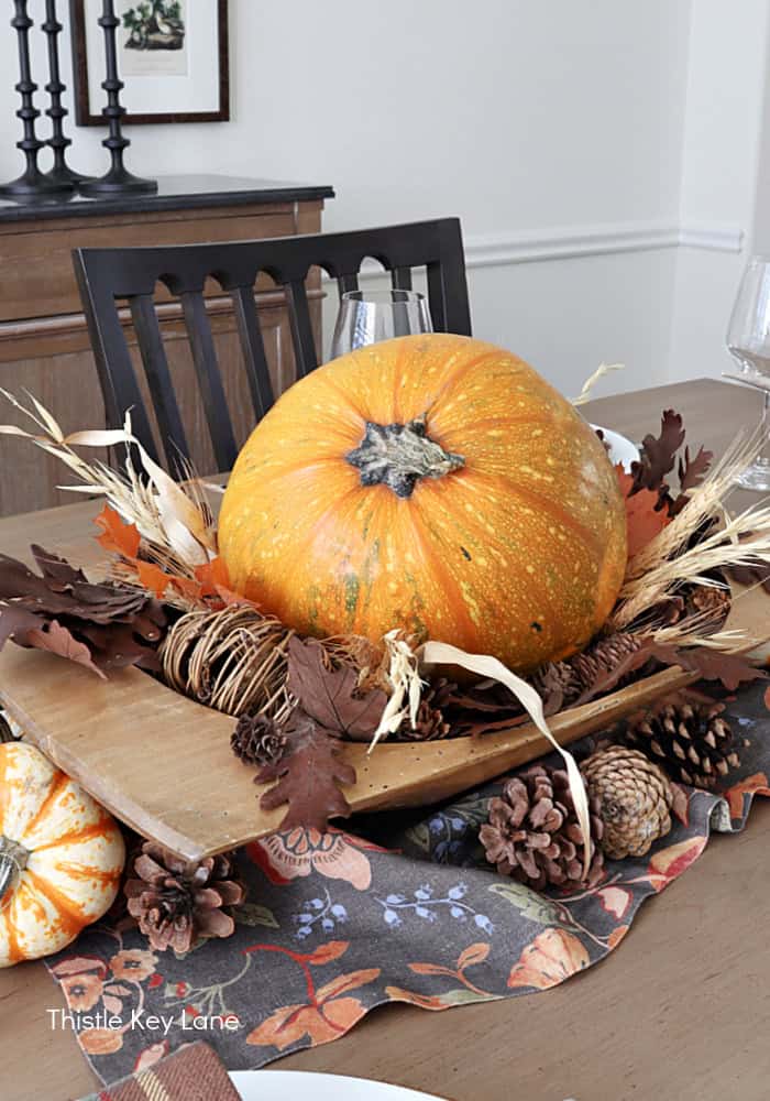 Pumpkin, wood bowl, leaves and pinecones. Rustic Thanksgiving Pumpkin Centerpiece And Tablescape.