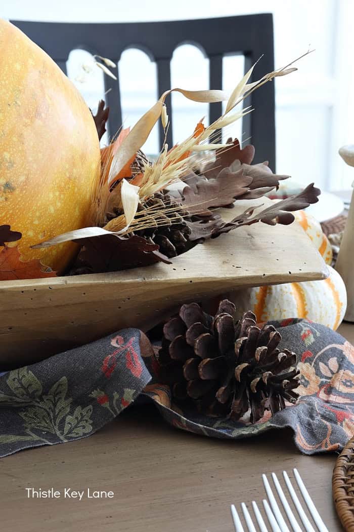 Dried stems, pine cones, and leaves with orange pumpkin. Rustic Thanksgiving Pumpkin Centerpiece And Tablescape.