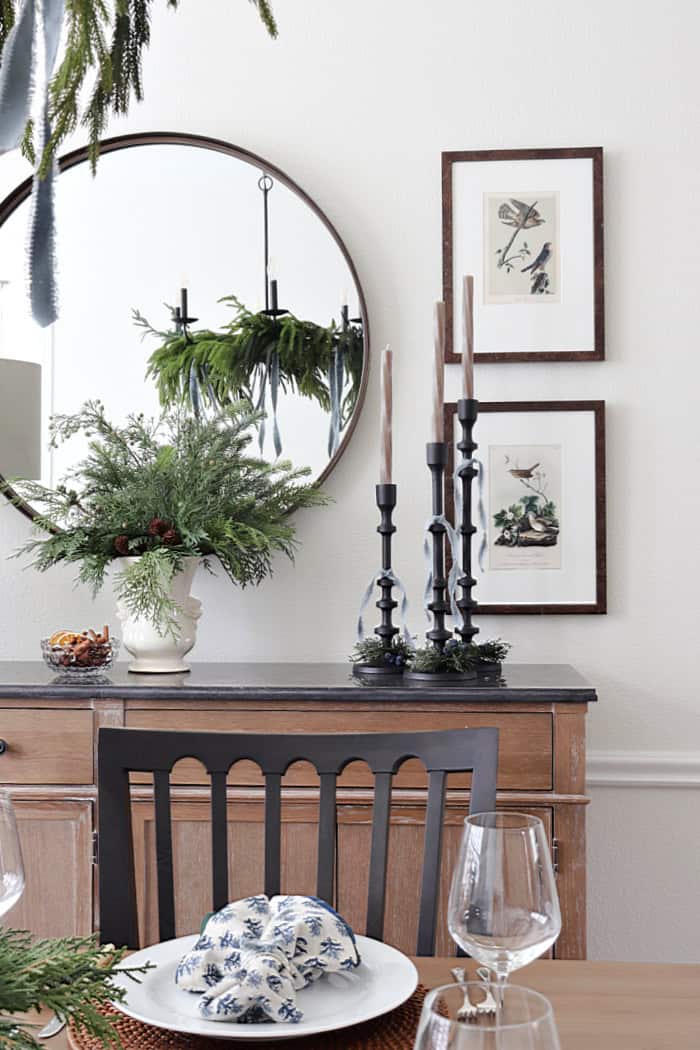 Vintage artwork and candles on buffett. Holiday Dining Room With Festive Greenery.
