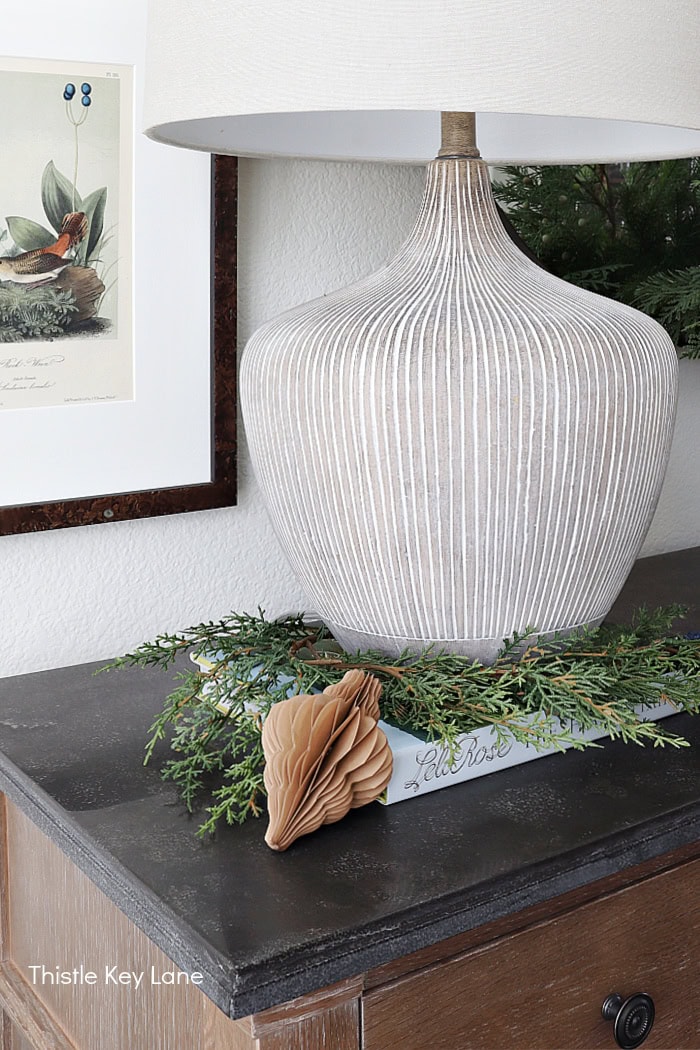Greenery and a paper ornaments next to a lamp. Holiday Dining Room With Festive Greenery.