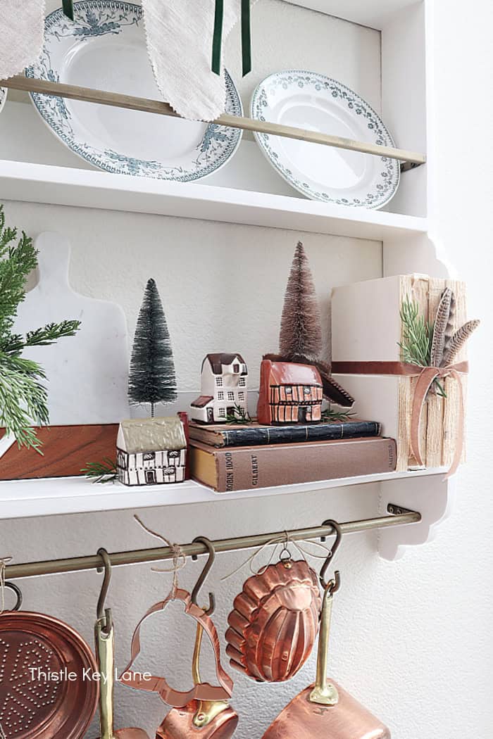English cottages on a shelf with books and bottle brush trees. How To Decorate With Homemade Stockings.