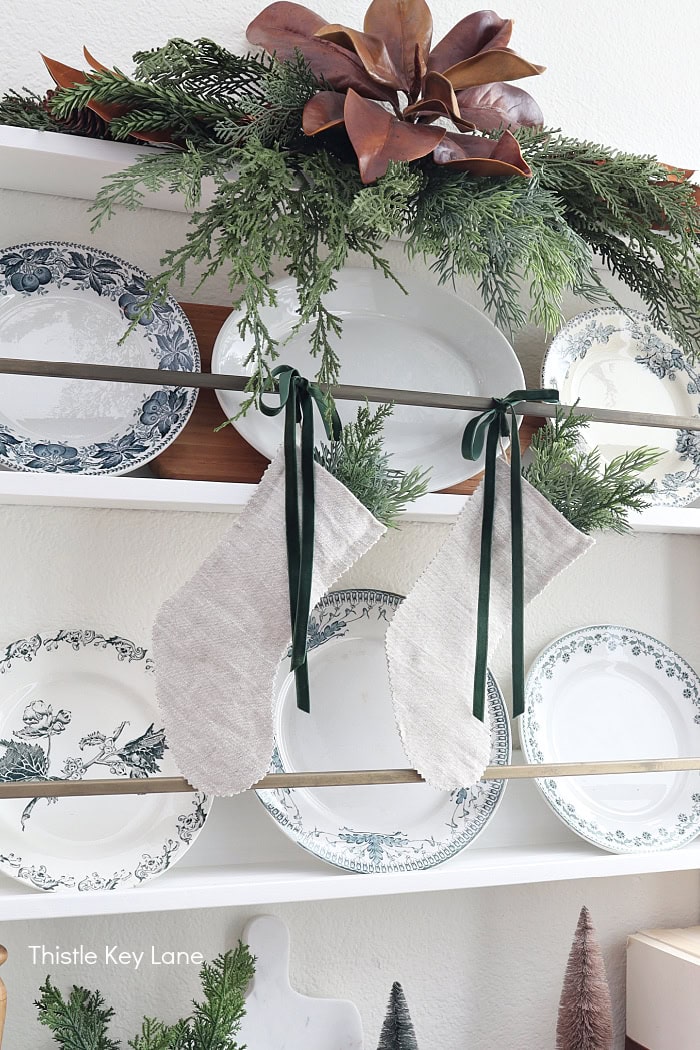 Magnolia leaves and greenery on a wall plate rack. How To Decorate With Homemade Stockings.
