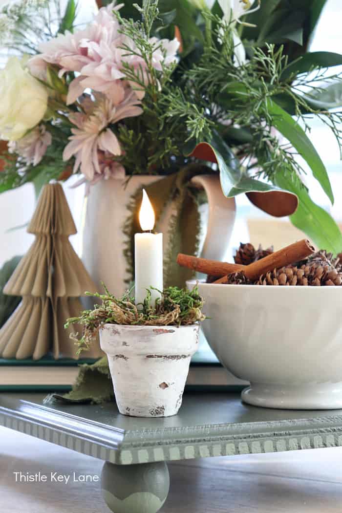 Mini tapered candle in a terracotta pot with moss. Holiday Floral Vignette With DIY Flameless Candle Holder.