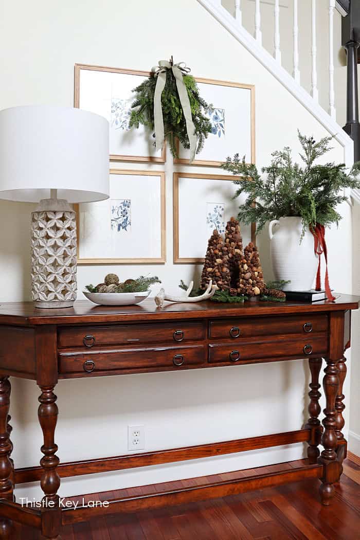 Lamp, large evergreen arrangement and Christmas swag. Create A Rustic Entry Table With Holiday Greenery,