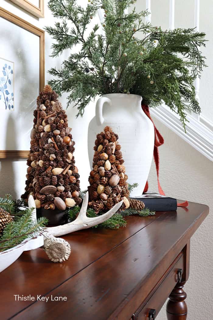 Deer shed, pinecone trees and vase. Create A Rustic Entry Table With Holiday Greenery.