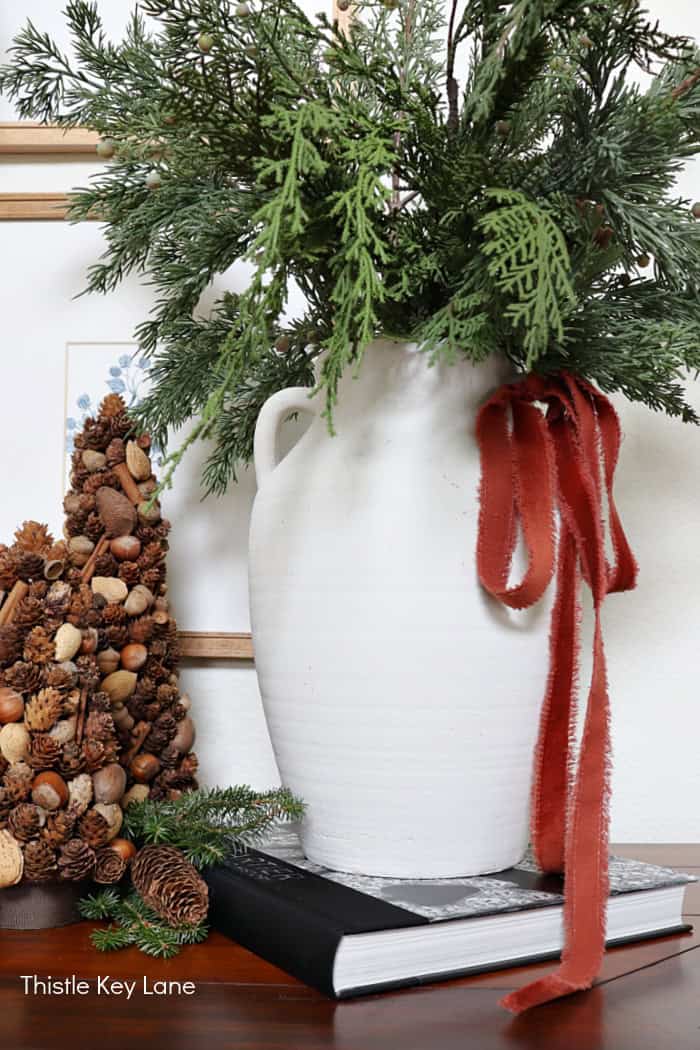 Large evergreen arrangement in white vase.