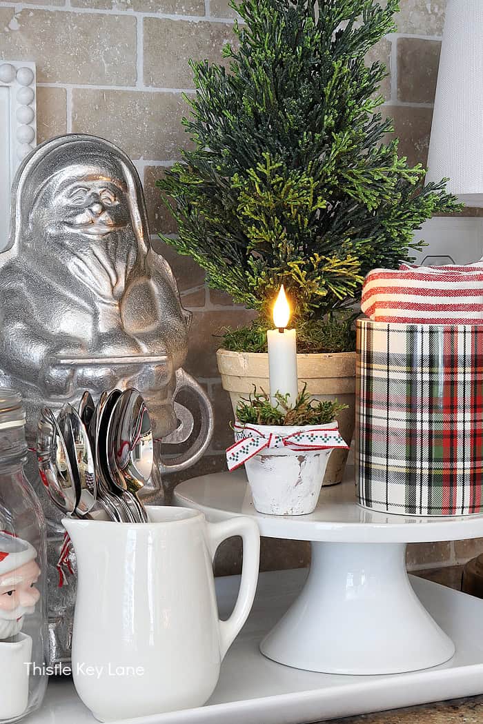 Flamless candle in a tiny flower pot, plaid mugs and a Santa cake mold.