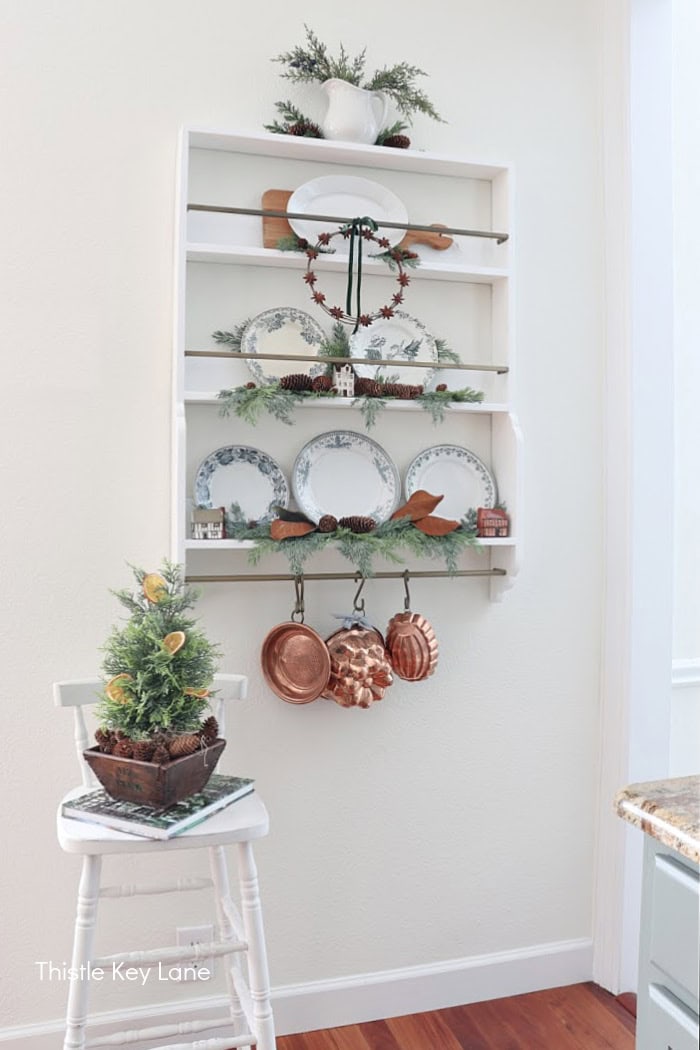 Wall plate rack with plates arranged in a tree shape. Simple Vintage Holiday Kitchen Ideas.
