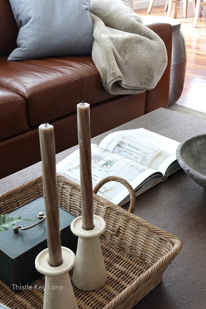 Coffee table with open book candle sticks and gray bowl.