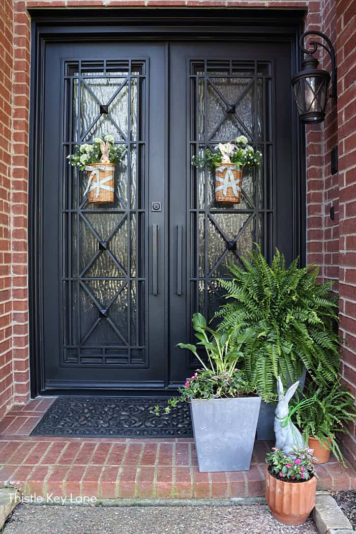 Black double doors with spring flowers and baskets. Spring Porch Refresh With Bunnies.