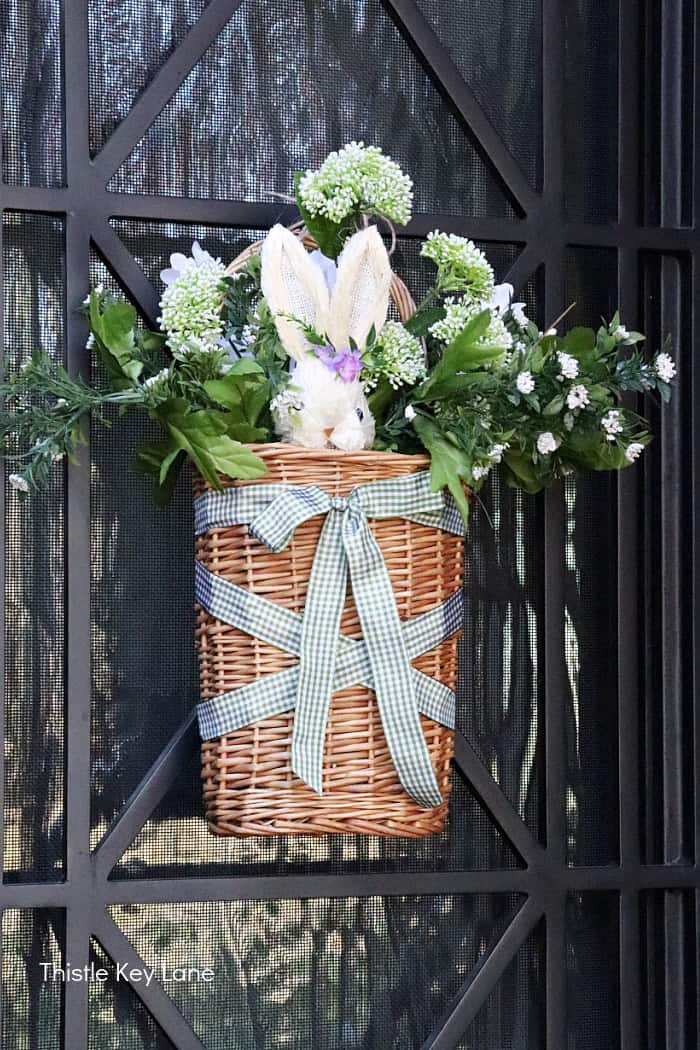 White bunny pick in a door basket with ribbon. Spring Porch Refresh With Bunnies.
