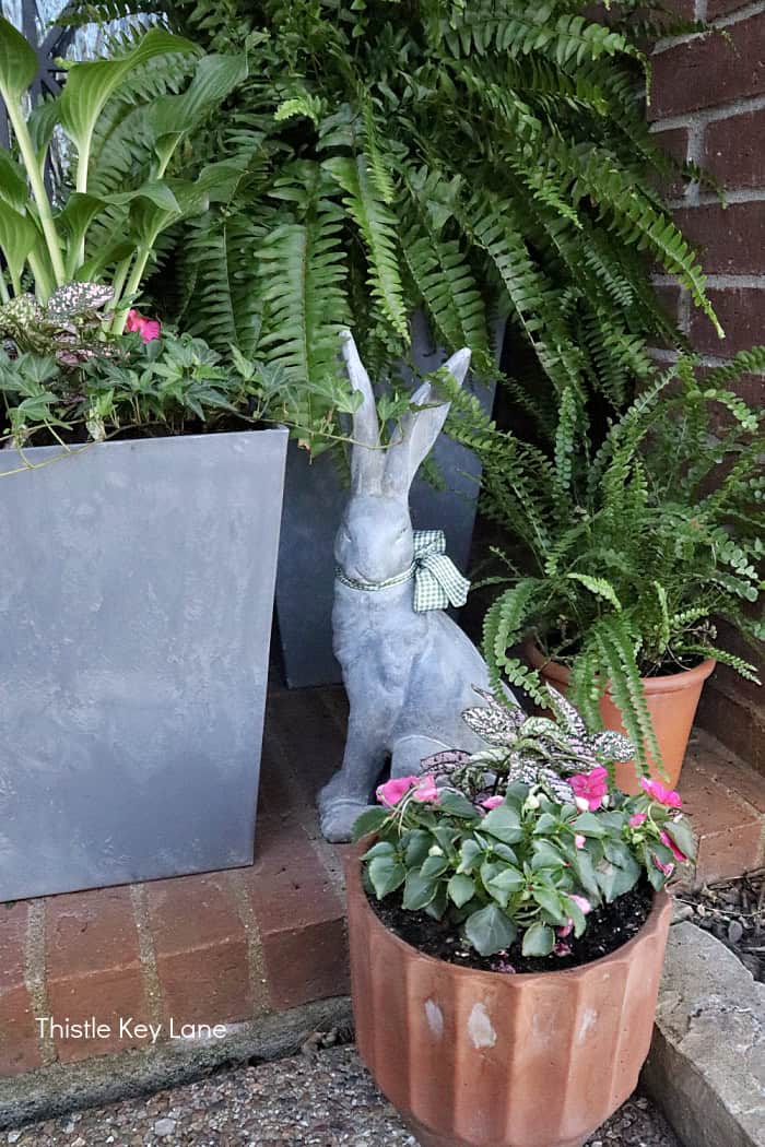 Rabbit figurine on the porch with flower pots.