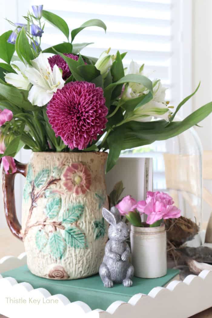 Pink and purple flowers in a vases pitcher. Vintage Vignette For Spring.