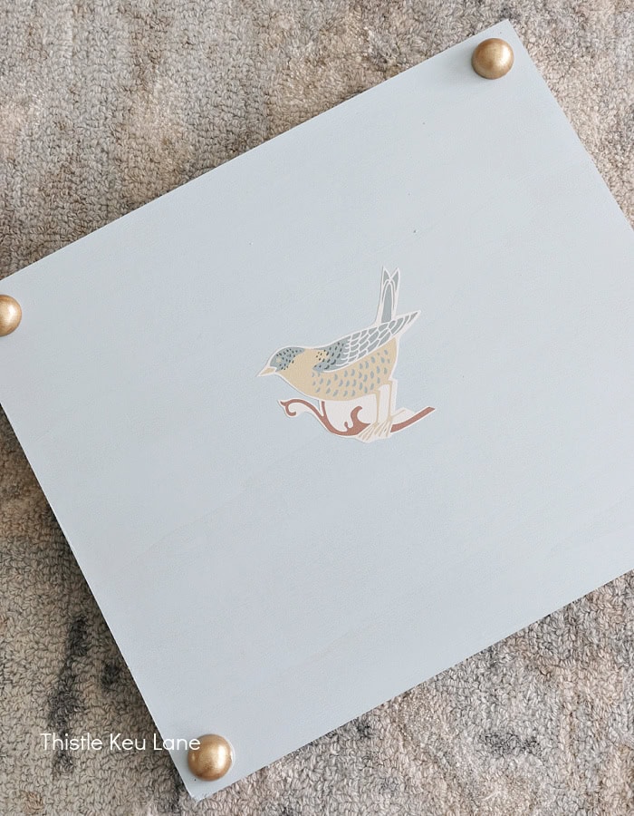 Bottom of tray with wallpaper cutout and gold feet.